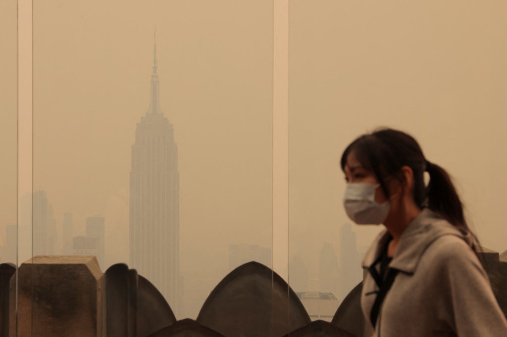 A person wears a mask as the Empire State Building is shrouded in smoke.